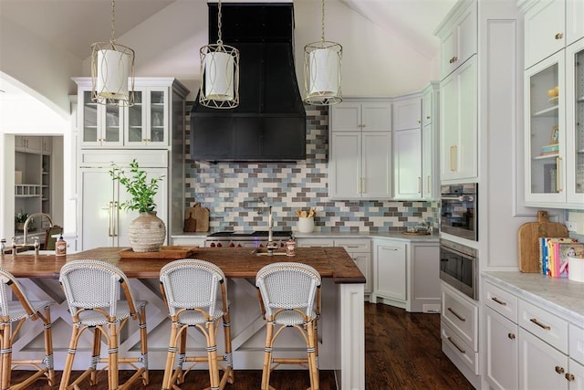 kitchen featuring vaulted ceiling, tasteful backsplash, a sink, pendant lighting, and a kitchen breakfast bar