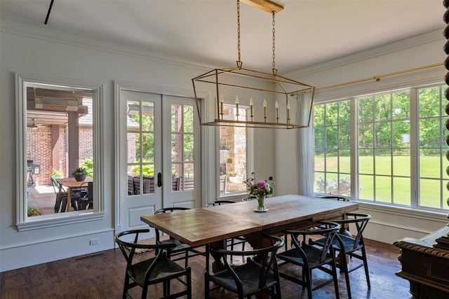 dining room with dark wood finished floors, ornamental molding, a chandelier, and french doors