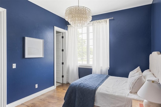 bedroom with wood finished floors, a chandelier, and baseboards