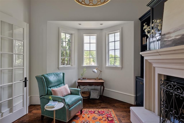 sitting room featuring dark wood-type flooring, a fireplace, and baseboards