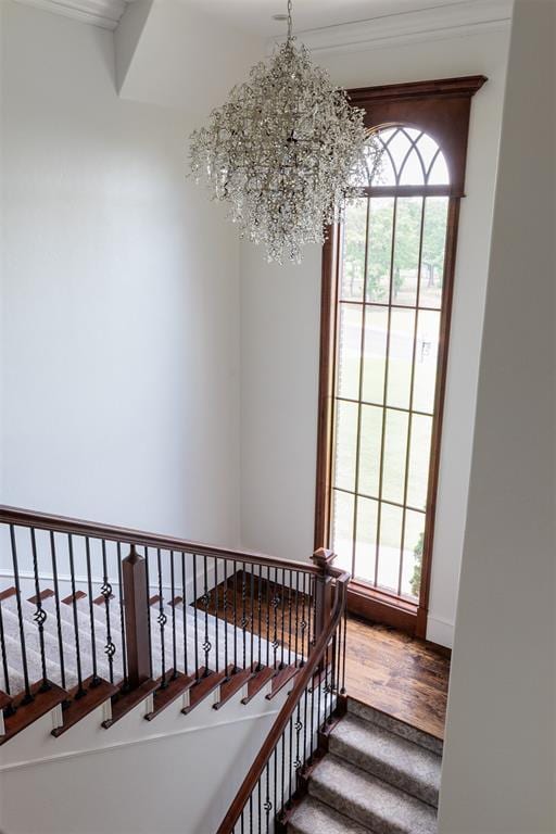 staircase featuring wood finished floors, a chandelier, and baseboards