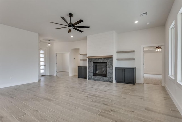 unfurnished living room with a ceiling fan, visible vents, and a healthy amount of sunlight
