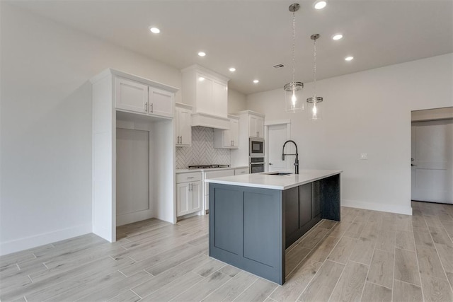 kitchen featuring appliances with stainless steel finishes, tasteful backsplash, a sink, light countertops, and white cabinetry