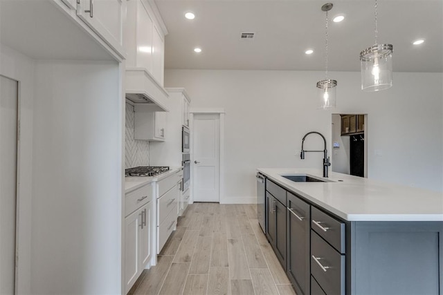 kitchen featuring a kitchen island with sink, visible vents, appliances with stainless steel finishes, a sink, and white cabinets