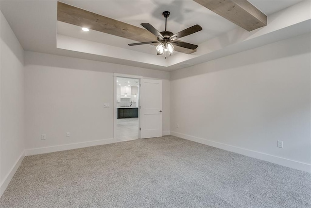 spare room featuring a ceiling fan, beamed ceiling, baseboards, a tray ceiling, and carpet flooring