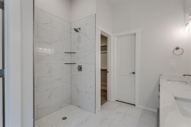 bathroom with a sink, baseboards, a tile shower, and marble finish floor
