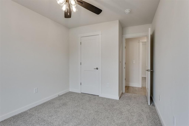 unfurnished bedroom with a ceiling fan, baseboards, and light colored carpet