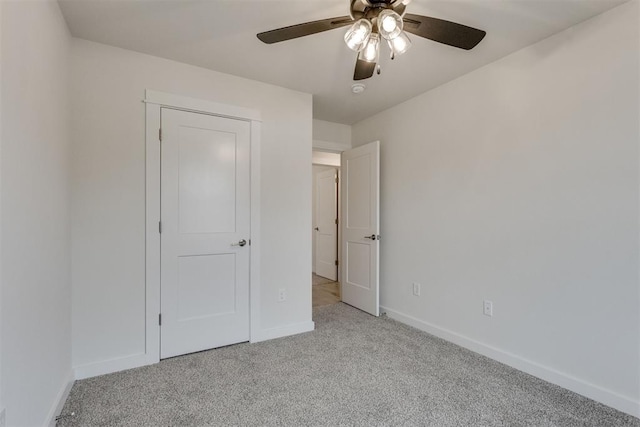 unfurnished bedroom featuring baseboards, light carpet, and a ceiling fan