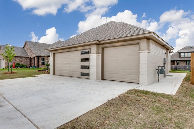 exterior space featuring a garage, driveway, roof with shingles, and brick siding