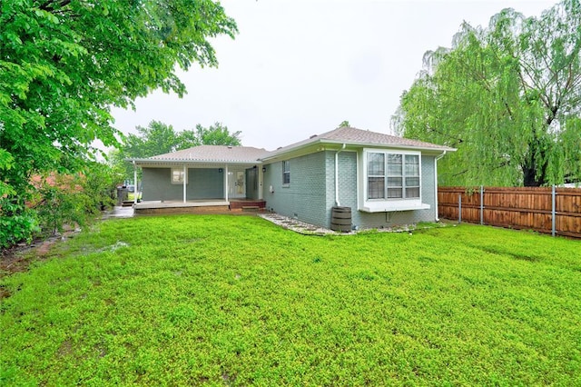back of house featuring brick siding, fence, and a yard