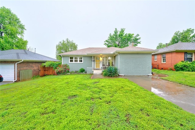 ranch-style house featuring fence, a front yard, brick siding, an attached garage, and driveway
