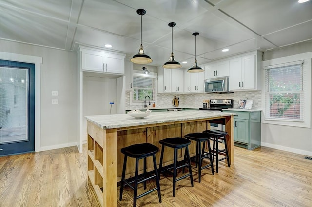 kitchen featuring baseboards, plenty of natural light, white cabinets, and stainless steel appliances