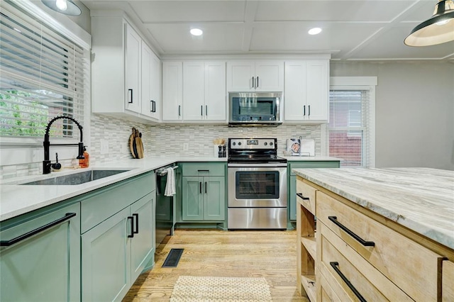 kitchen with green cabinetry, appliances with stainless steel finishes, a sink, a wealth of natural light, and visible vents