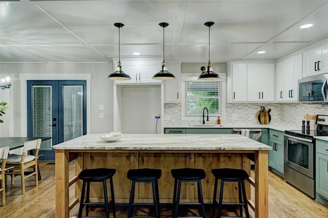 kitchen with a sink, white cabinets, light wood-style floors, and stainless steel appliances