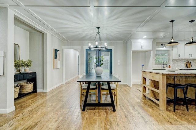 dining area with an inviting chandelier, light wood-style floors, and baseboards