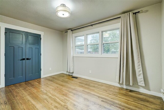 spare room with baseboards, light wood-type flooring, and visible vents