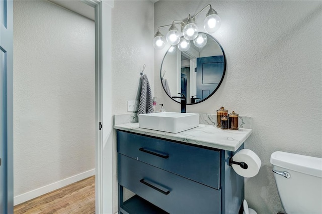 half bathroom featuring toilet, baseboards, wood finished floors, and vanity