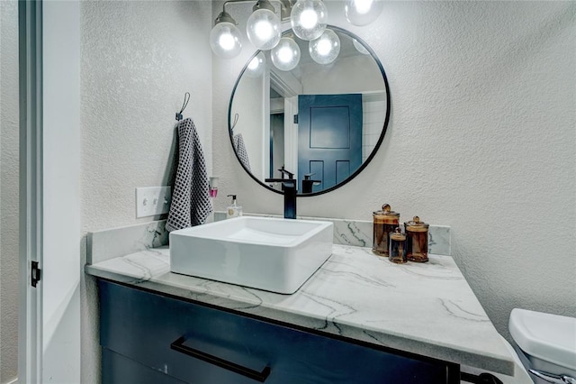 half bath featuring vanity and a textured wall