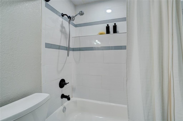 bathroom with a textured wall, shower / bath combo with shower curtain, and toilet