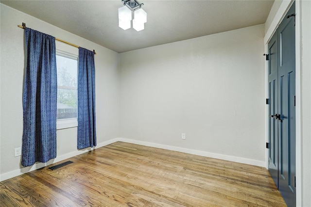 spare room with baseboards, visible vents, and light wood-type flooring