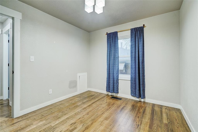unfurnished room featuring baseboards, visible vents, and wood finished floors