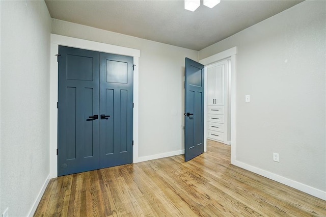 unfurnished bedroom with baseboards, wood finished floors, and a closet