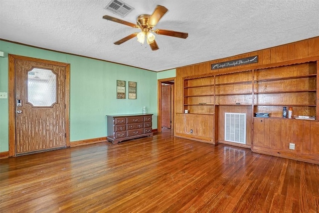 interior space with a textured ceiling, ceiling fan, visible vents, and hardwood / wood-style flooring