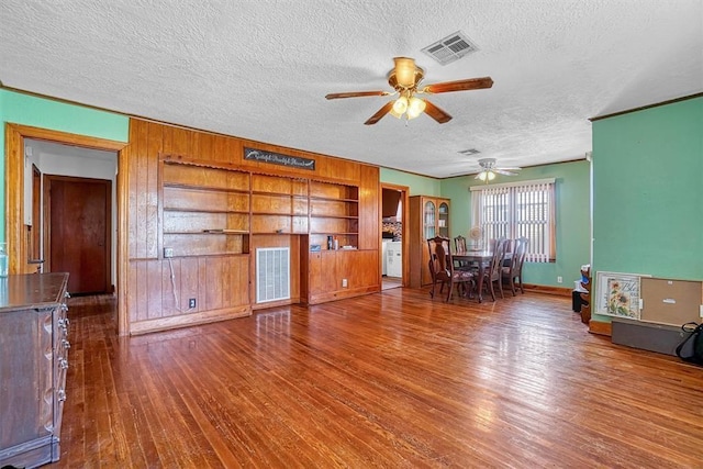 living room featuring a textured ceiling, ceiling fan, visible vents, and hardwood / wood-style floors
