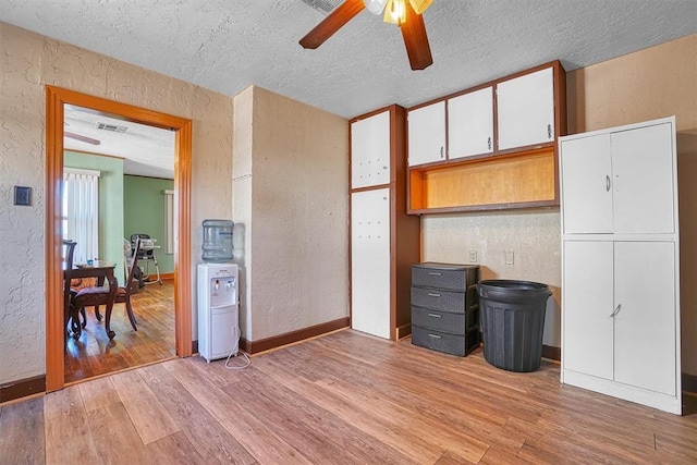 kitchen with light wood-style floors, a textured wall, a ceiling fan, and a textured ceiling