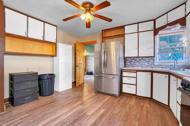 kitchen with ceiling fan, light countertops, freestanding refrigerator, light wood-style floors, and white cabinetry