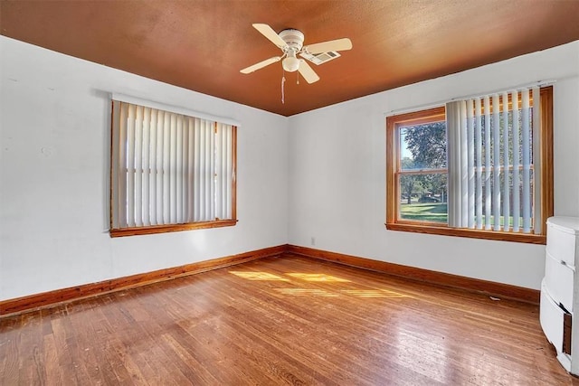 empty room featuring baseboards, ceiling fan, and wood finished floors
