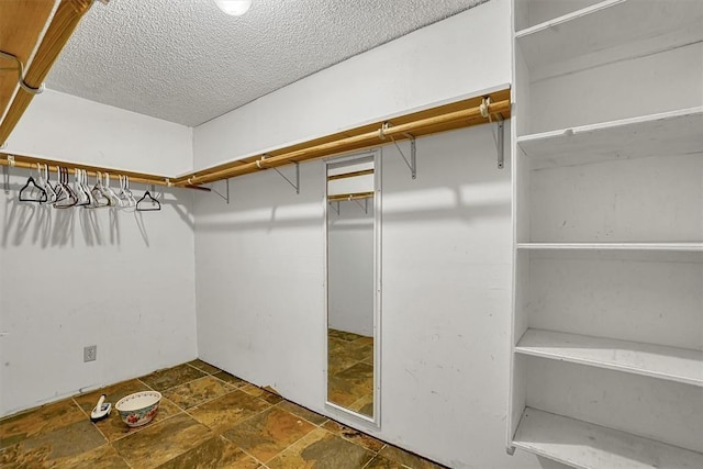 spacious closet featuring stone finish floor