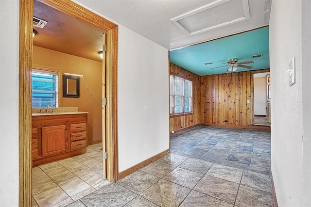 interior space featuring a sink, wood walls, attic access, baseboards, and visible vents