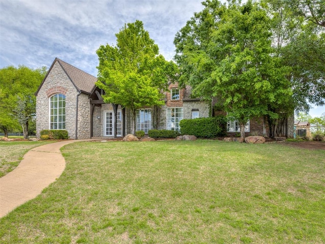view of front facade featuring french doors, a front lawn, and stone siding