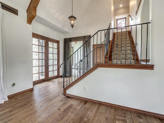 stairs featuring french doors, baseboards, wood finished floors, and high vaulted ceiling