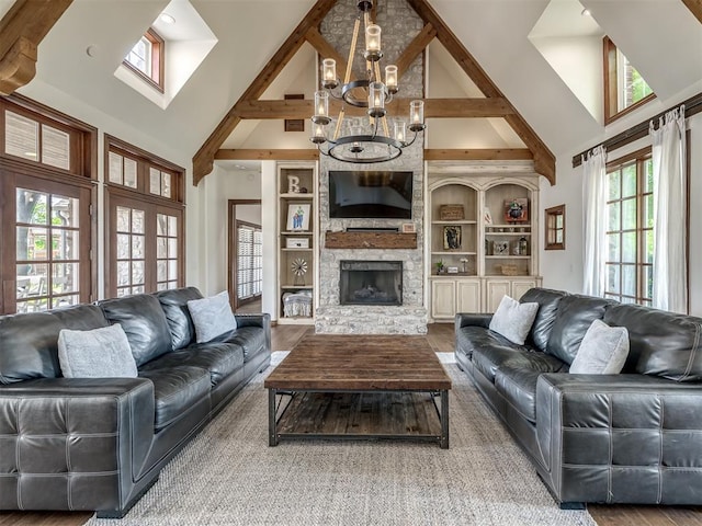living room with high vaulted ceiling, a fireplace, wood finished floors, and a notable chandelier