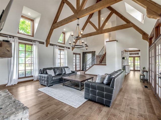 living area with french doors, a chandelier, high vaulted ceiling, and stairway
