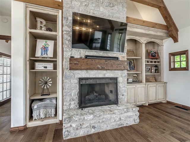 living room with a stone fireplace, built in shelves, beam ceiling, baseboards, and dark wood-type flooring