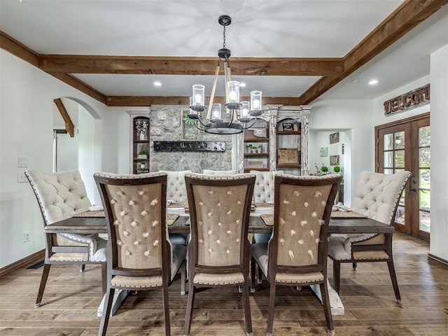 dining area with arched walkways, beamed ceiling, a notable chandelier, and wood finished floors