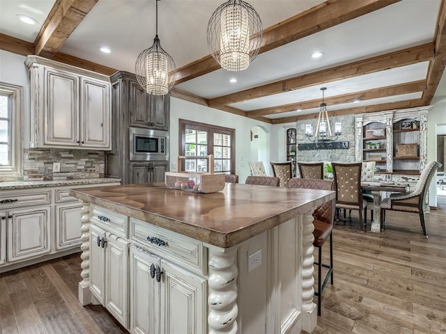 kitchen with beamed ceiling, recessed lighting, stainless steel microwave, and a notable chandelier