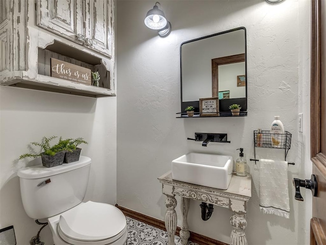 bathroom featuring baseboards, a sink, and toilet