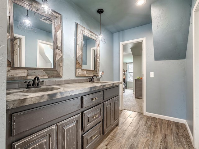 full bathroom with a sink, baseboards, double vanity, and wood finished floors