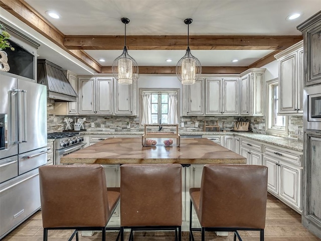 kitchen with a kitchen island, backsplash, premium range hood, and premium appliances