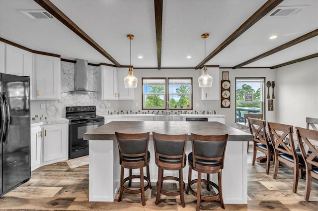25386 Patterson Rd, Tecumseh, OK 74873 - kitchen with wall chimney range hood, black appliances, light wood-style flooring, a kitchen island, and white cabinetry
