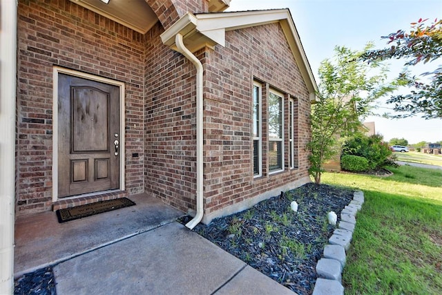property entrance featuring brick siding and a lawn