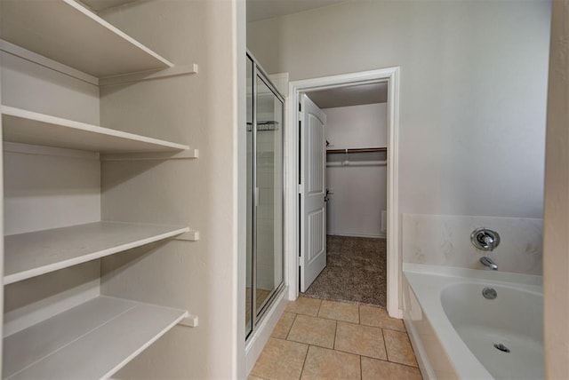 bathroom featuring a spacious closet, a shower stall, a bath, and tile patterned flooring