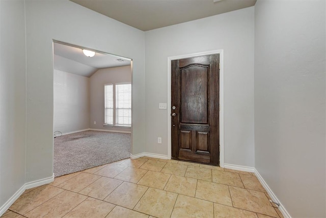 foyer with lofted ceiling, light tile patterned floors, baseboards, and light carpet