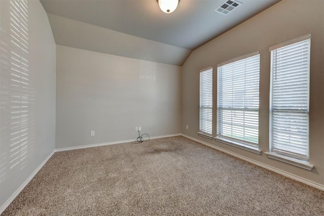 carpeted spare room featuring baseboards and vaulted ceiling