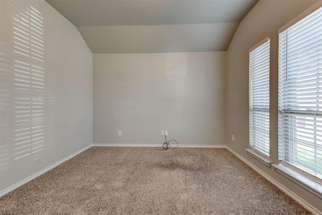 empty room with carpet, vaulted ceiling, and baseboards