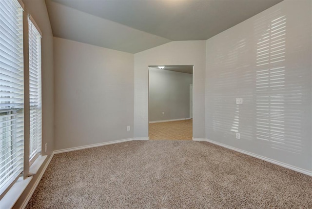 unfurnished room with light carpet, vaulted ceiling, and baseboards